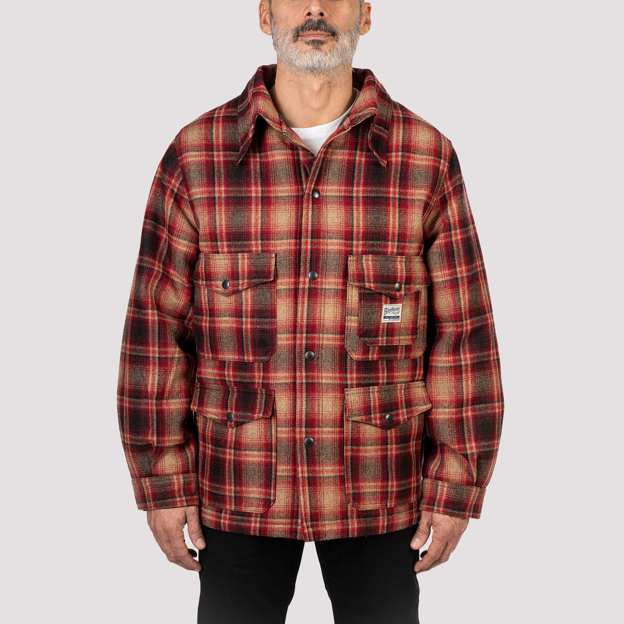 Man wearing a red and brown plaid jacket on a light gray background