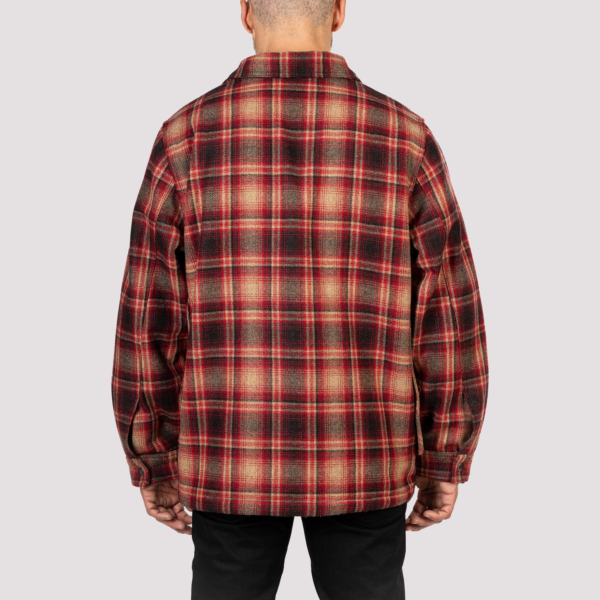 Person wearing a red and brown plaid shirt on a plain background